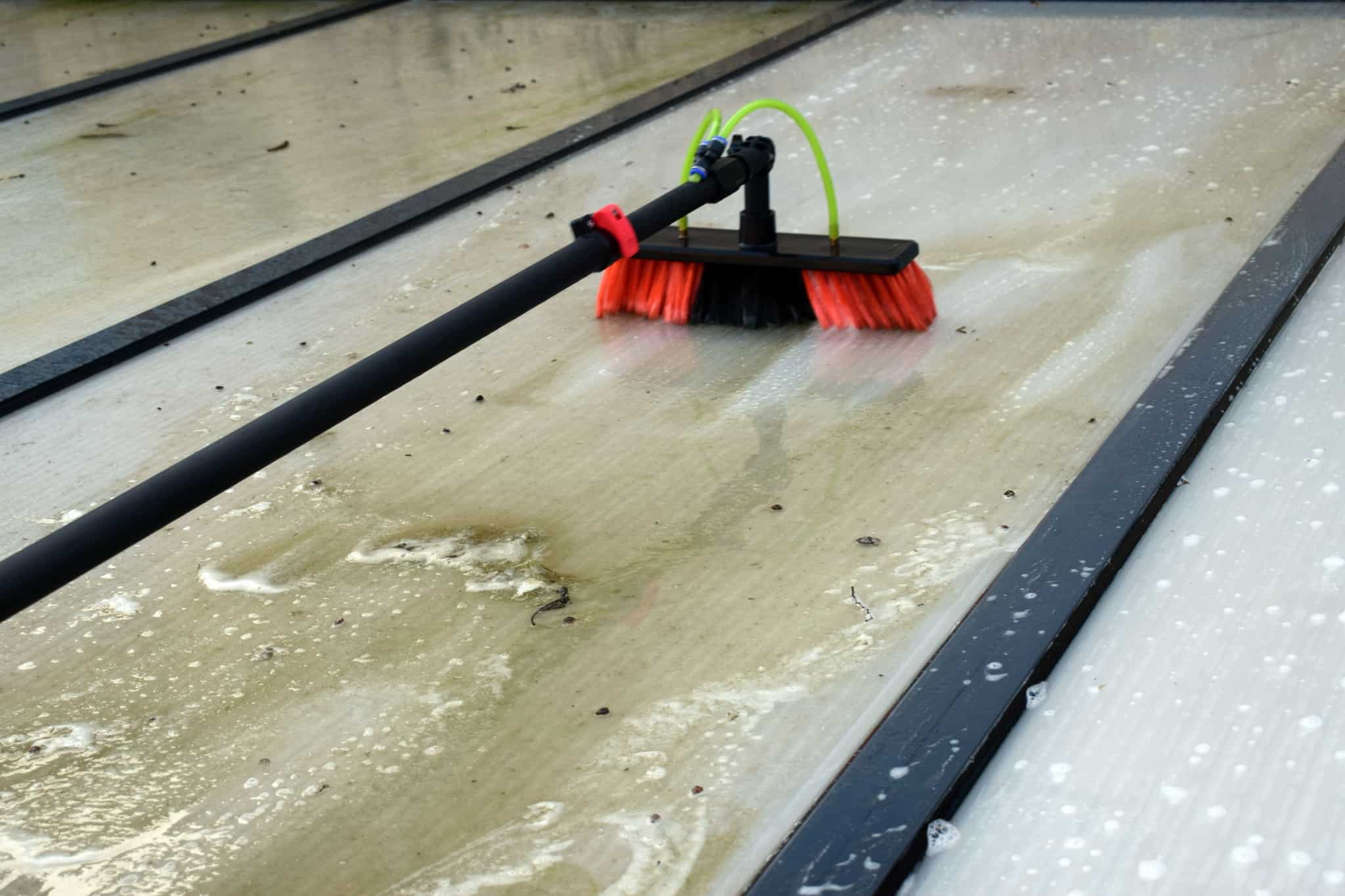 Schoonmaken terrasoverkapping met een telescoopsteel en -borstel